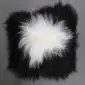 Square Icelandic sheepskin cushion with long, shaggy black wool and a large white spot in the centre.