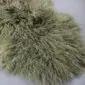 Close-up of a khaki Mongolian lambskin rug featuring long, curly wool fibres.