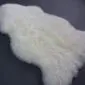IMG_3424 Two ivory white sheepskin rugs with thick, textured wool pile and natural curved edges.