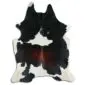 Natural cowhide rug with a large black and dark brown central patch surrounded by white and black spots.