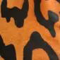Close-up of a jaguar print cowhide rug featuring black rosettes on an orange and tan background.