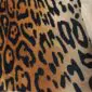 Close up of a cowhide rug featuring a tan and orange jaguar print with black spots.