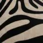 Close-up of a zebra print cowhide rug showing black stripes on a beige background.