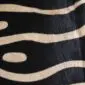 Close-up of a zebra print cowhide rug showing black and cream wavy stripes and natural hair texture.