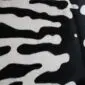 Close-up of a cowhide rug featuring a black and white tiger print pattern. detail view