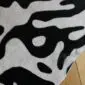 Close-up of a cowhide rug featuring a black and white tiger print pattern. detail view detail view