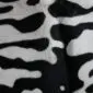 Close-up of a cowhide rug featuring a black and white tiger print pattern. detail view