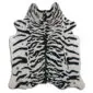 Irregularly shaped cowhide rug featuring a white base with black tiger-style stripes.