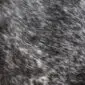 Close-up of a speckled cowhide rug with a mix of grey, black, and white natural hair fibres.