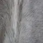 Close-up of a grey cowhide rug showing natural hair texture and a vertical white stripe.