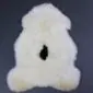 Cream rare breed sheepskin rug with thick, curly wool and a natural organic shape on a dark grey background.