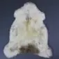 Natural cream rare breed sheepskin rug with grey and brown markings and a thick, textured wool pile.