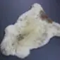 Natural cream rare breed sheepskin rug with brown and grey markings and a thick, textured wool pile.