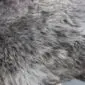 Close up of a rare breed sheepskin rug with long, thick grey and white wool fibres.