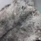 Close-up of a thick, long-pile sheepskin rug with mottled grey, cream, and brown wool fibres.