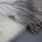 Close-up of a multi-layered sheepskin rug featuring long, thick wool in shades of grey and cream.