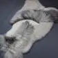 Large multi-layered sheepskin rug with long grey and white wool in an irregular shape.