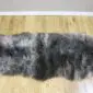 A long, double-length sheepskin rug with thick, mottled grey and charcoal wool on a wooden floor.