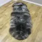 Long double sheepskin rug with thick, mottled grey and cream wool pile on a wooden floor.