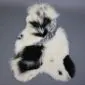 Large multi-layered sheepskin rug with irregular patches of cream, white, and black long-pile wool.