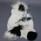 Large multi-layered sheepskin rug with long white wool and irregular black patches.