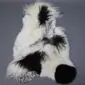 Large multi-layered sheepskin rug with long white and black wool patches in an irregular shape.