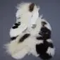 Large multi-layered sheepskin rug with long white wool and dark brown patches on a grey background.