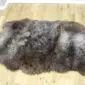 Large triple sheepskin rug with long, textured wool in mottled shades of grey, brown, and cream.