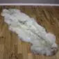 Long double rare breed sheepskin rug with natural cream, grey and brown wool on a wooden floor.