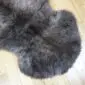 Close up of a thick, curly rare breed double sheepskin rug in mottled grey and charcoal tones.