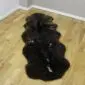 Long double sheepskin rug with thick, dark brown and black textured wool in a natural organic shape.