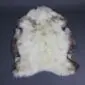 Natural rare breed sheepskin rug with cream wool and dark brown mottled edges in an organic shape.
